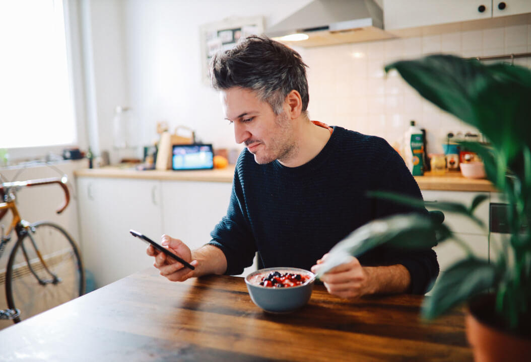 man looking at phone in kitchen